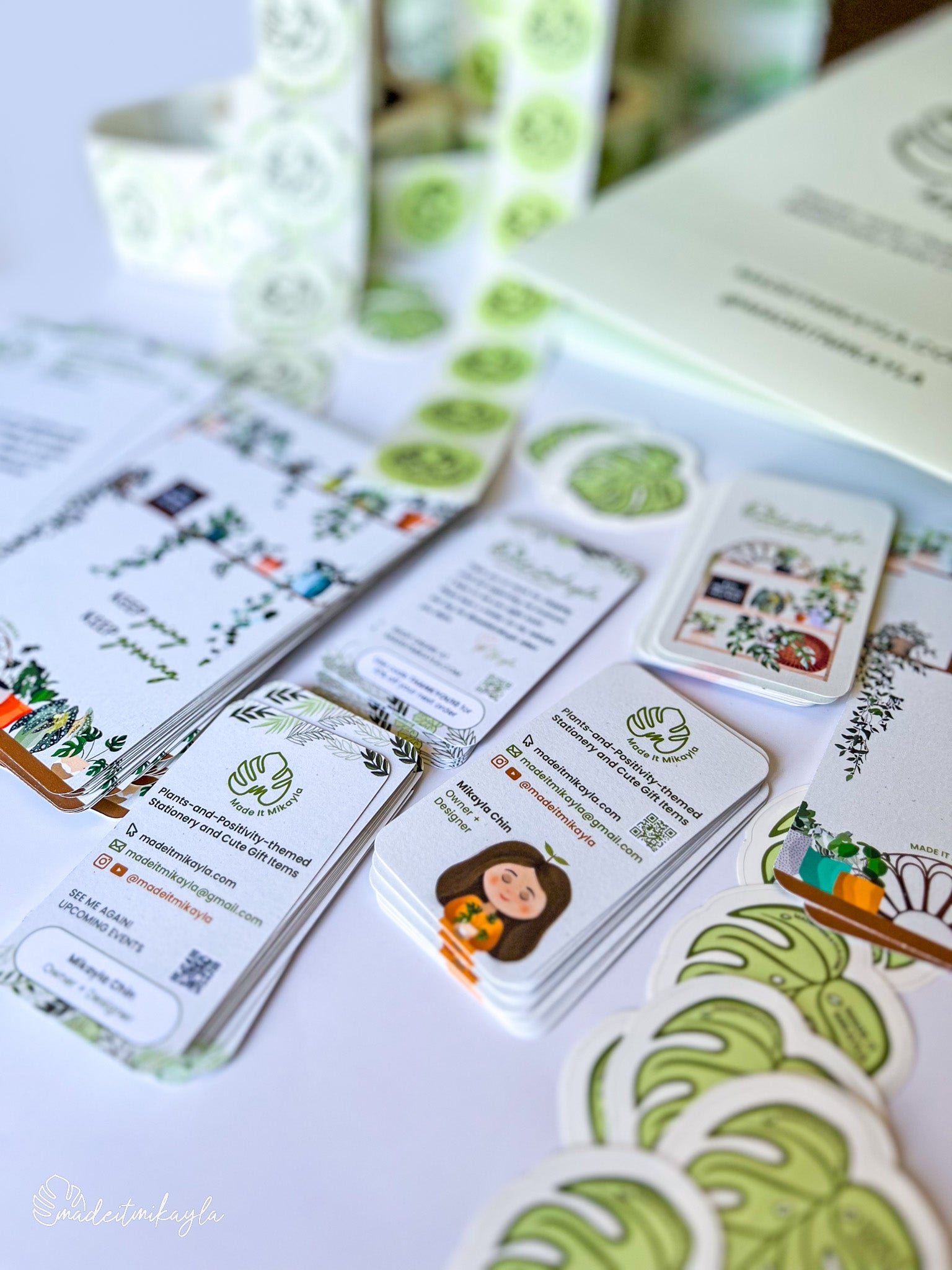 Collection of MadeItMikayla branded business cards and stickers with a focus on green and white design.