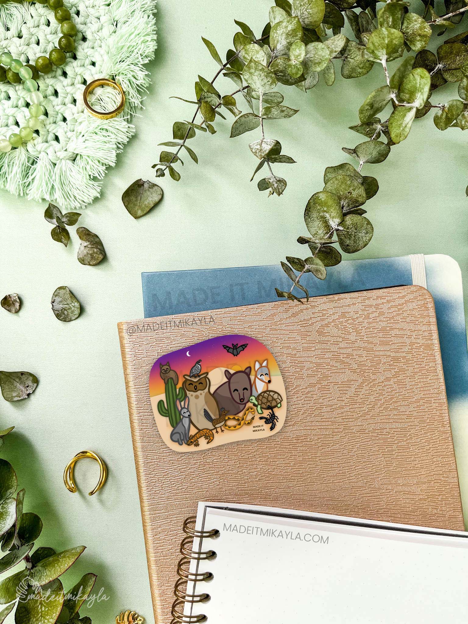 Sticker featuring desert animals: javelina, bobcat, owl, quail, jackrabbit, gila monster, roadrunner, tortoise, coyote, bat, scorpion, snake. Sunset background with a cactus.