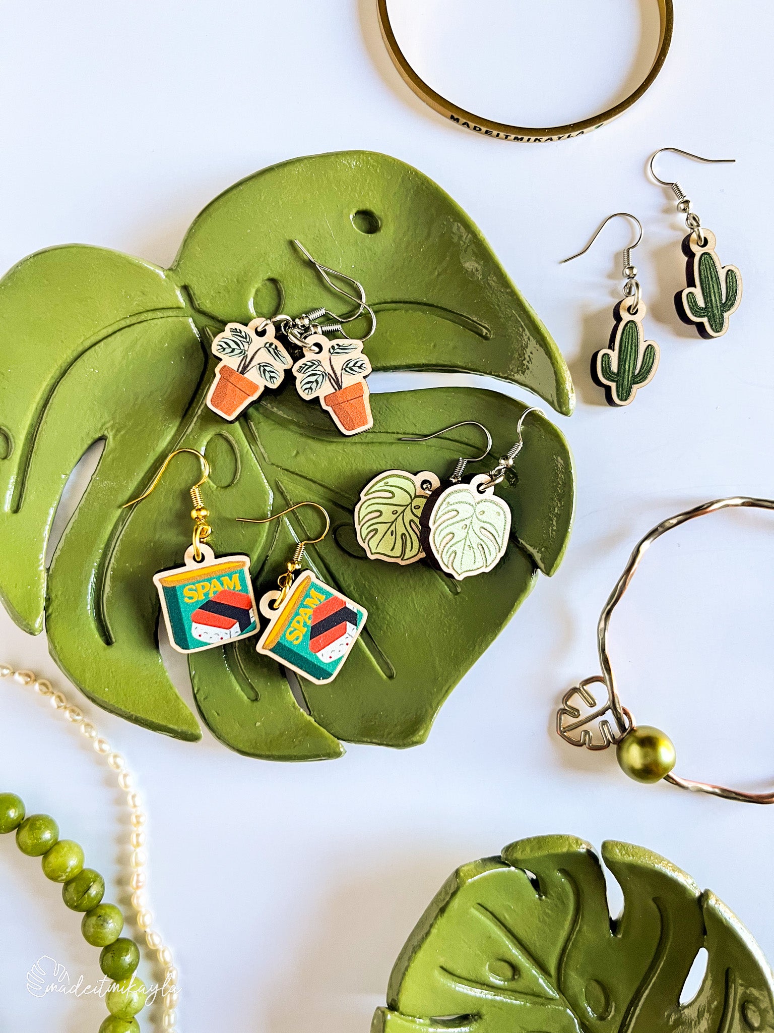 Jewelry set including dangle wood earrings displayed on a green leaf-shaped trinket dish.