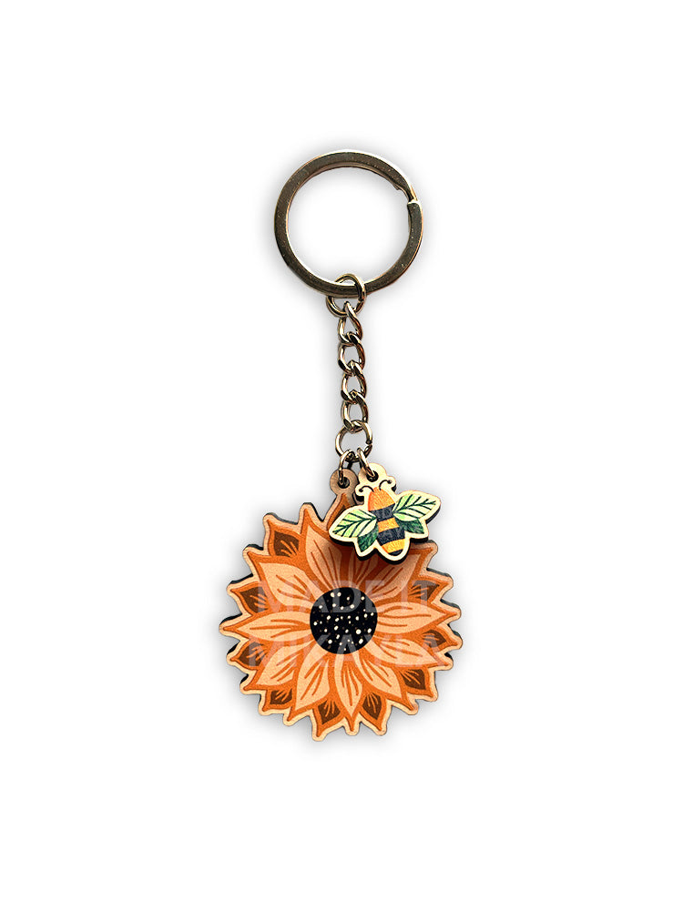 Sunflower-shaped keychain with a bee leaf charm and silver chain on a white background