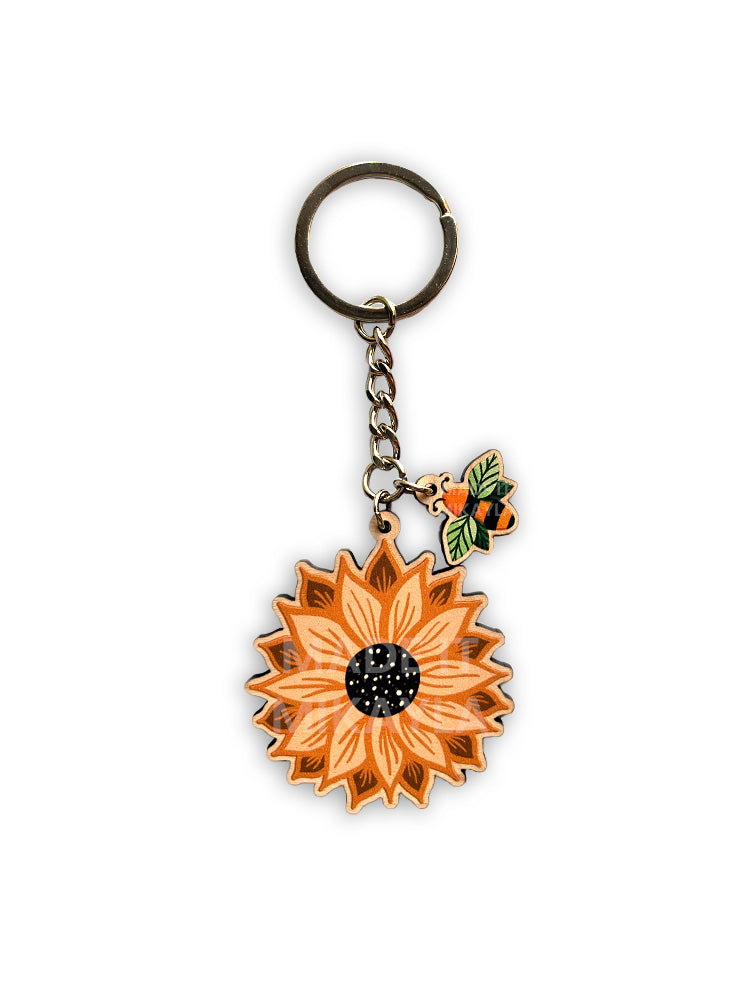Sunflower-shaped keychain with a bee leaf charm and silver chain on a white background